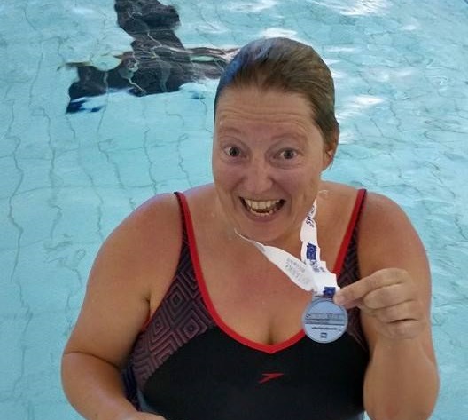 Inge Dowden holding Swimathon medal in the pool